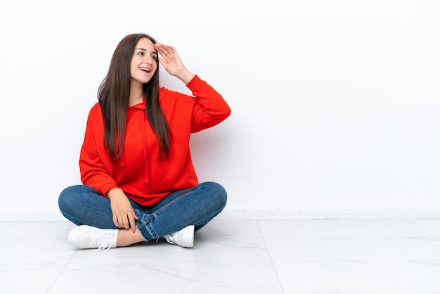 A jovem ucraniana sentada no chão isolada no fundo branco percebeu algo e pretendeu a solução