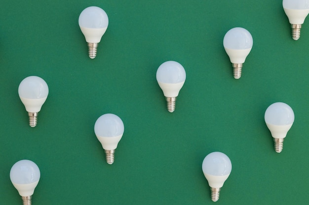 A lâmpada LED está sobre um fundo verde pastel Conceito de economia de energia Minimalismo vista superior
