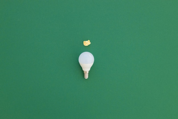 A lâmpada LED está sobre um fundo verde pastel Conceito de economia de energia Minimalismo vista superior