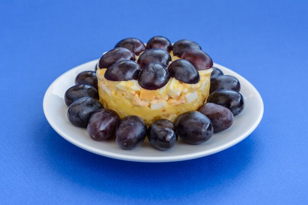 A lendária salada Tiffany em camadas com uvas, frango e queijo no fundo azul. O nome vem do apelido da senhora que postou a receita da salada no portal de culinária.