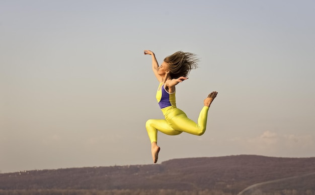 A liberdade é o esporte da vida em movimento cheio de energia A jovem e atraente mulher esportiva se exercita no ginásio ao ar livre, exercício matinal Ginasta nacional ucraniana Acrobacia e garota de ginástica pulando alto