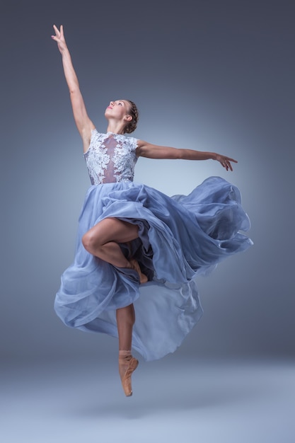 A linda bailarina dançando em um vestido longo azul sobre fundo azul