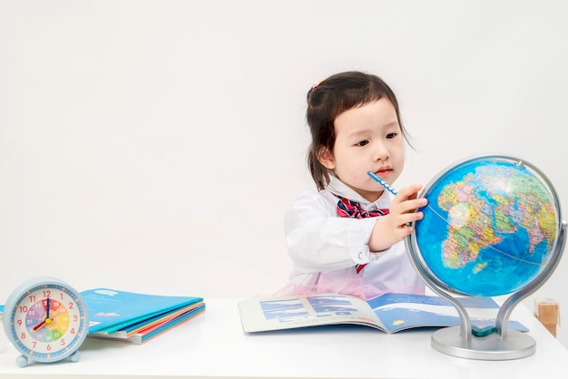 A linda garotinha está aprendendo geografia em sua mesa