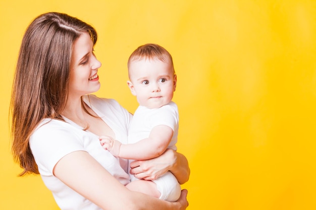 A linda mãe segura nas mãos o lindo bebê e sorri