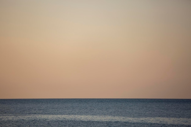 A linha azul da água do mar calma e do céu noturno amarelo