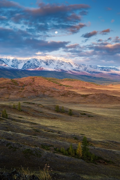 A lua sobre a cordilheira do Norte Chuysky, amanhecer. Outono nas montanhas Altai. Rússia