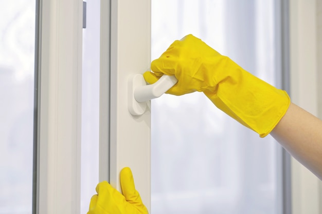 A luva protetora de borracha amarela abre e fecha a janela de plástico, PVC