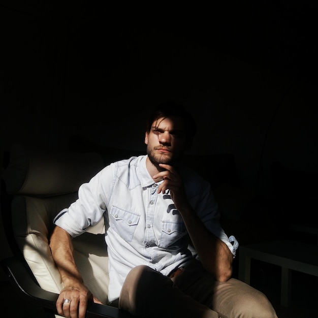 A luz do sol a cair sobre um homem pensativo na cadeira.