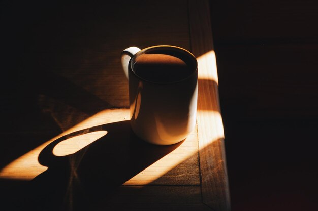 Foto a luz do sol caindo no café na xícara na mesa.