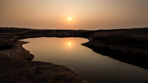 A luz do sol na cena da manhã e a silhueta do pequeno turista refletem na frente da água no grand canyon Sam Phan Bok Ubon Ratchathani Tailândia