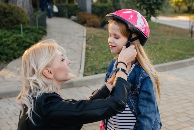 A mãe ajuda a arrumar o equipamento e o capacete da filha para um passeio de segway no parque