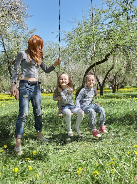 A mãe balança os filhos no balanço do jardim