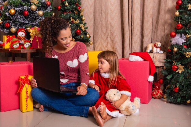 A mãe da família e a filha usam o laptop em casa nas férias de natal.