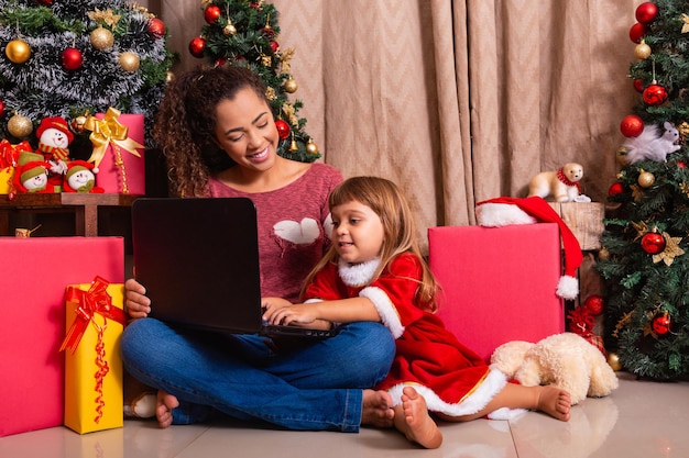 A mãe da família e a filha usam o laptop em casa nas férias de natal.