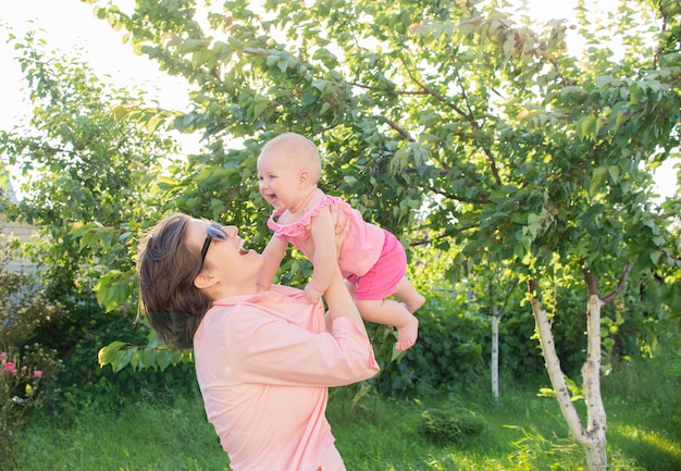 A mãe e a filha estão rindo e se divertindo ao ar livre, no jardim lá fora.