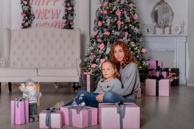 A mãe e a filha sentadas no chão perto da árvore de Natal na sala de Natal