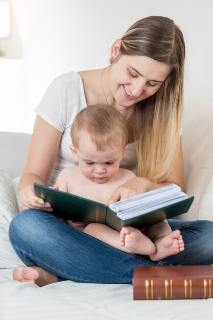 A mãe e o filho de 9 meses, sentados no sofá, a ler um grande livro