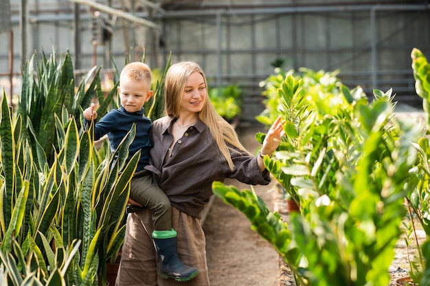 A mãe e o filho olham para as plantas na estufa