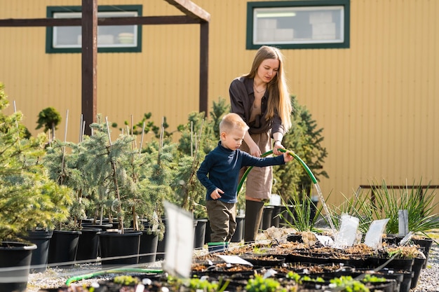 A mãe e o filho pequeno regam os vasos de plantas