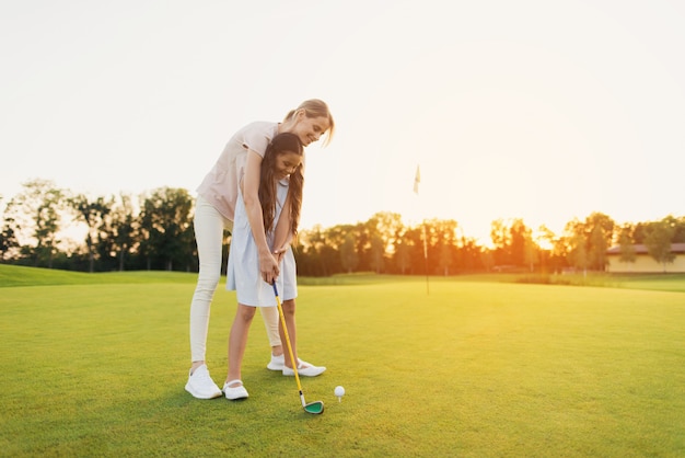 A mãe ensina a criança tomar o passatempo Golfing da família do tiro.