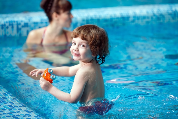 A mãe ensina uma criança a nadar na piscina.