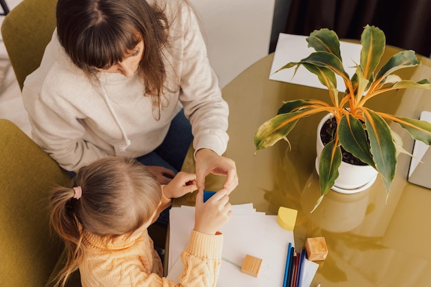 A mãe está brincando com a filha. A mãe e a menina construíram uma torre de blocos coloridos.