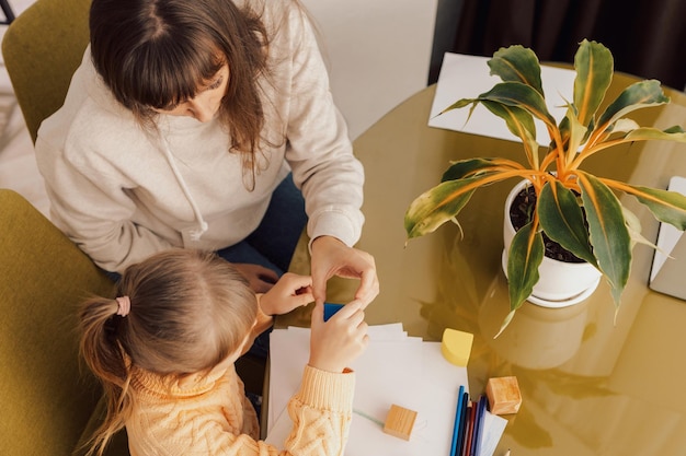 A mãe está brincando com a filha. A mãe e a menina construíram uma torre de blocos coloridos.