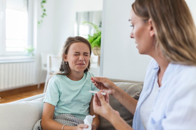 A mãe está fazendo o teste rápido de covid-19 em casa para a filha doente em casa. Mãe realizando esfregaço nasal em seu filho, dando o exemplo para analisar se o paciente é positivo para doenças infecciosas