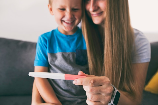 Foto a mãe está mostrando ao filho o teste de gravidez