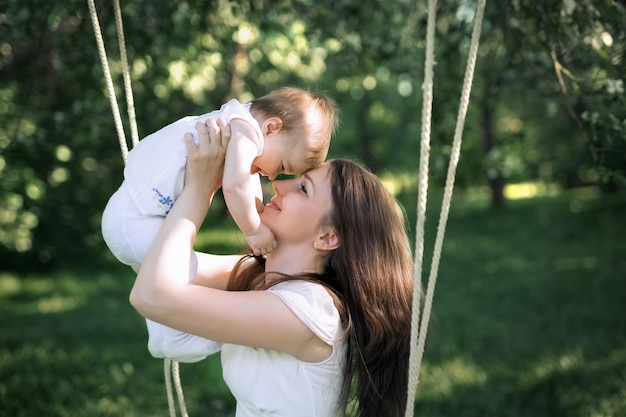 A mãe está segurando sua filha nos braços, gentilmente encostando sua testa contra a testa da criança