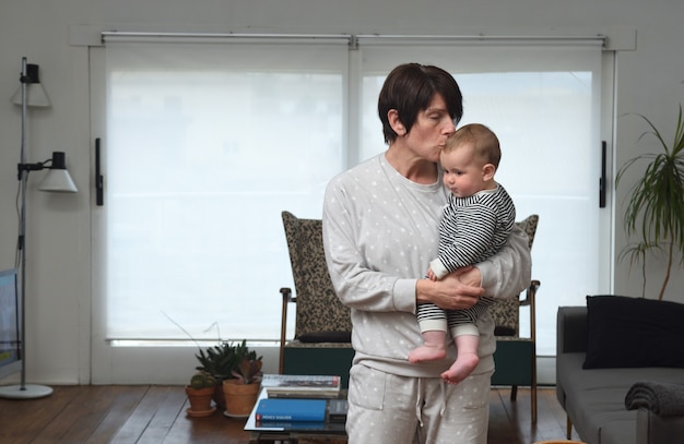 A mãe que segura o bebê e lhe dá um beijo