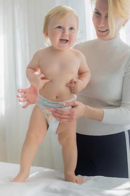 Foto a mãe segura o bebé na mesa de massagem, feliz, a mãe e o bebé a rir.