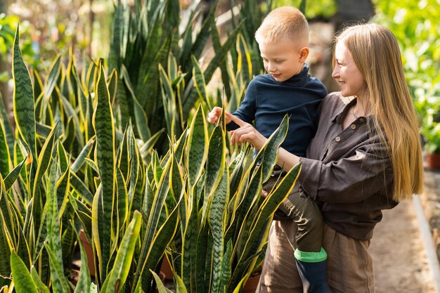 A mãe segura o filho nos braços e mostra-lhe as plantas