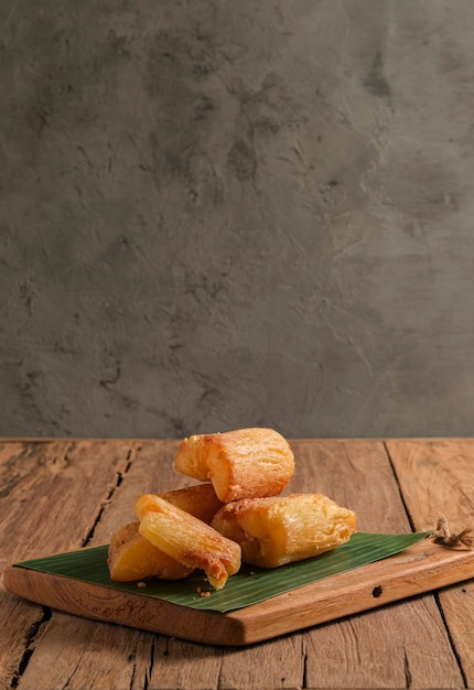 A mandioca frita é servida em uma tábua de cortar com base de folha de bananeira. Organizado de tal forma com um tema clássico de mesa de cozinha