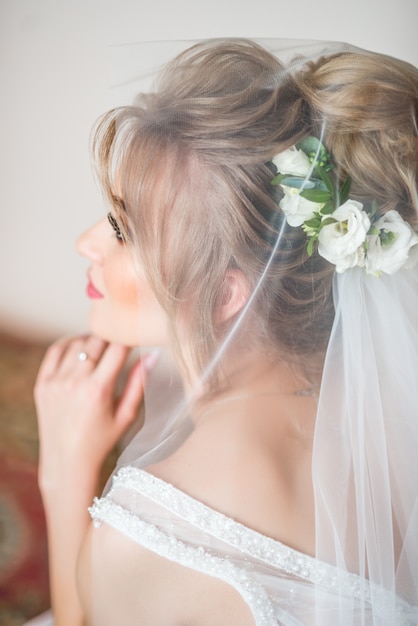 A manhã do casamento. Belo retrato da noiva coberto com um véu. Os olhos olham para baixo. penteado com flores frescas.