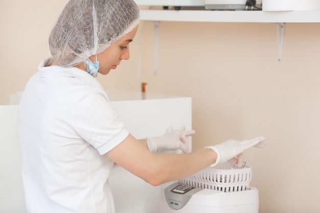 A manicure esteriliza suas ferramentas na autoclave ou no forno. Mestre no salão, preparando seus instrumentos para desinfecção.