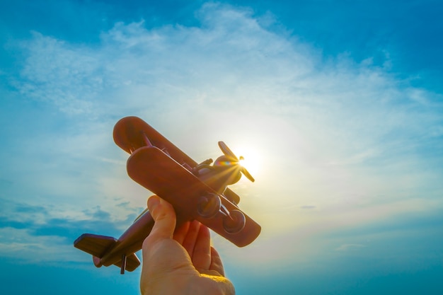 A mão com um avião de brinquedo no fundo do nascer do sol