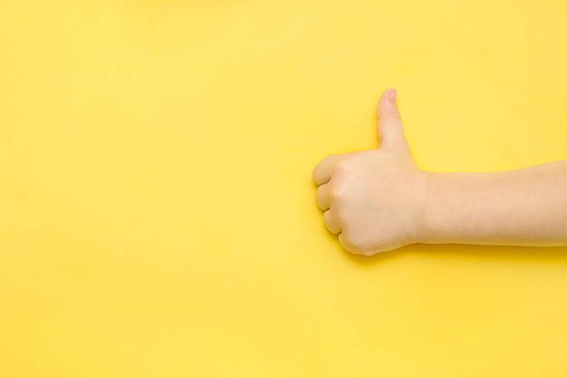 A mão da criança mostra um gosto em um fundo azul com um espaço de cópia