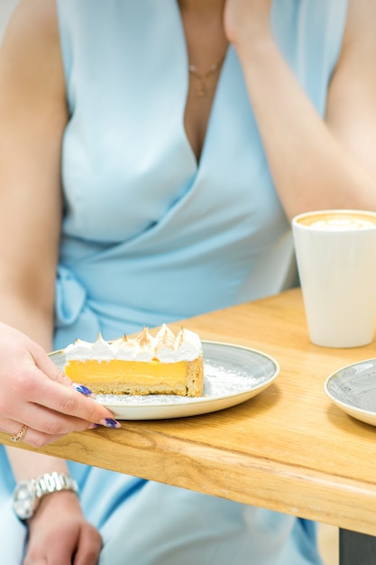 Foto a mão da garçonete coloca o pedaço de bolinho na mesa em um café, a mão de uma mulher está colocando em volta