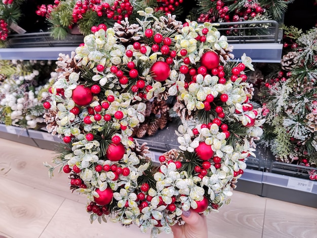 A mão da garota que está no shopping está segurando uma guirlanda de natal.