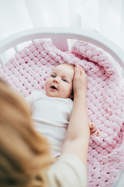 Foto a mão da mãe acariciando a cabeça do bebê na cama