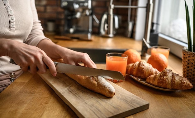 A mão da menina cortou a baguete francesa com faca