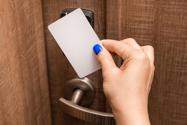 A mão da mulher coloca o cartão-chave no painel abrindo a porta do quarto de hotel pessoa do sexo feminino com unhas azuis abrindo a porta