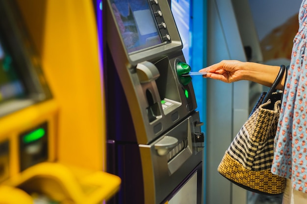 A mão da mulher insere um cartão de crédito em uma máquina atm