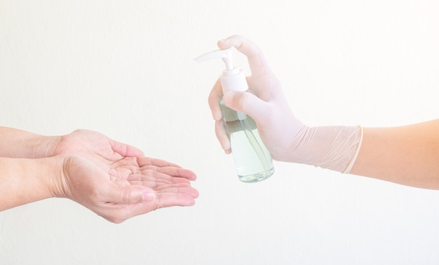 A mão da mulher pressionando o gel de álcool do frasco da bomba para limpar as mãos e prevenir a infecção por coronavírus, autocuidado inicial durante uma crise epidêmica. conceito de autoproteção e saúde.