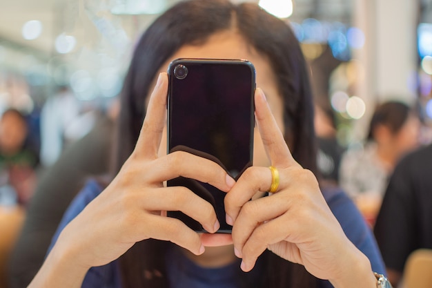 A mão da mulher que guarda o telefone esperto com fundo do borrão.