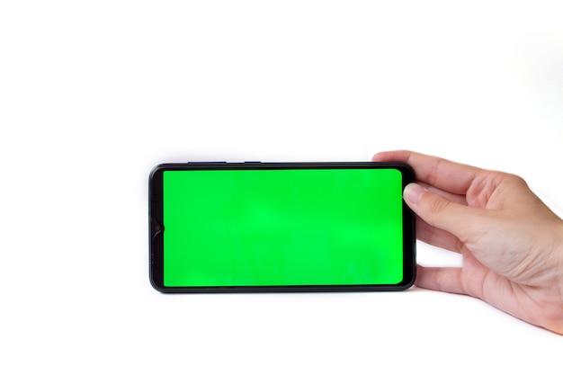 A mão da mulher segura o smartphone na posição horizontal com uma tela verde sobre fundo branco, chroma key, mock up.