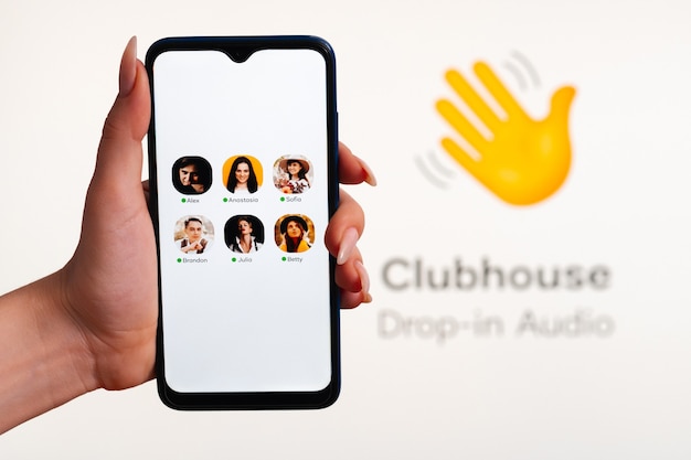 A mão da mulher segura um smartphone com a interface do app club house na tela. o áudio do clubhouse dropin é um aplicativo de mídia social ativado por voz.