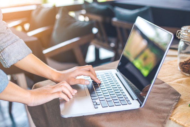 A mão da mulher trabalha em um portátil do computador no escritório.