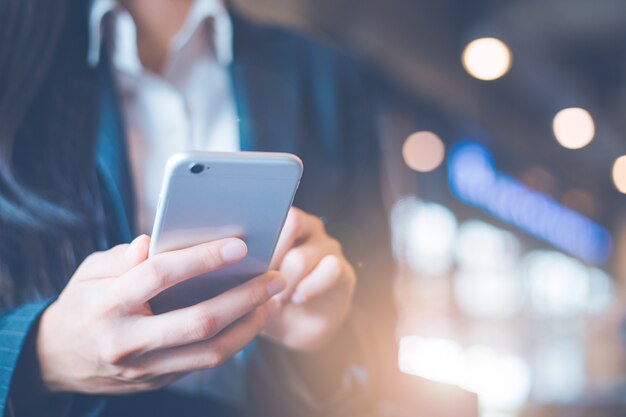 A mão das mulheres de negócio está usando telefones celulares no escritório.